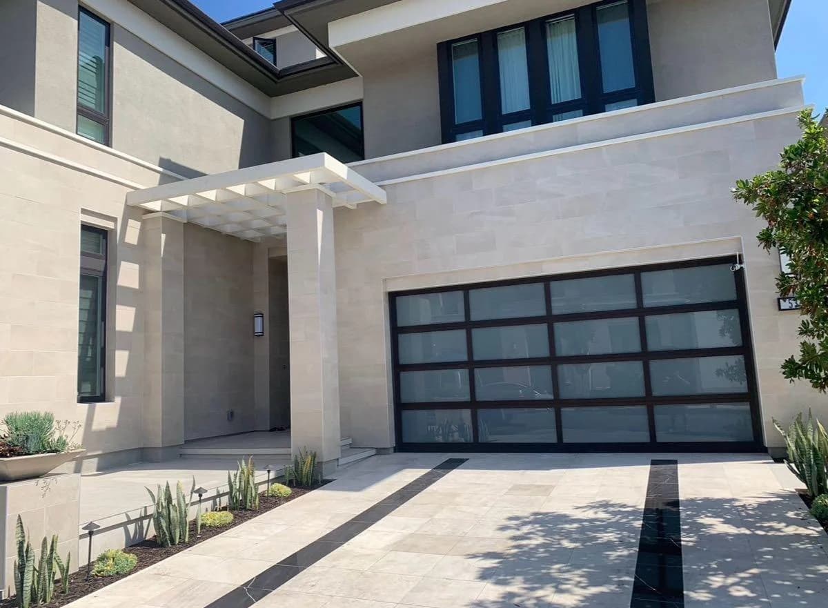 Black-framed glass garage door at a stone-clad home, photographed in Protex Access’s business gallery